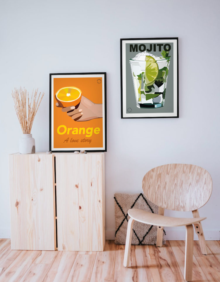 Lyst rum med lyst trægulv, en stol i lyst træ og en lille komode hvor der står en Kreativ Kunstplakat i grafisk design på, med en hånd der holder en appelsin. På væggen hænger en Kreativ Kunstplakat i grafisk design af en mojito.