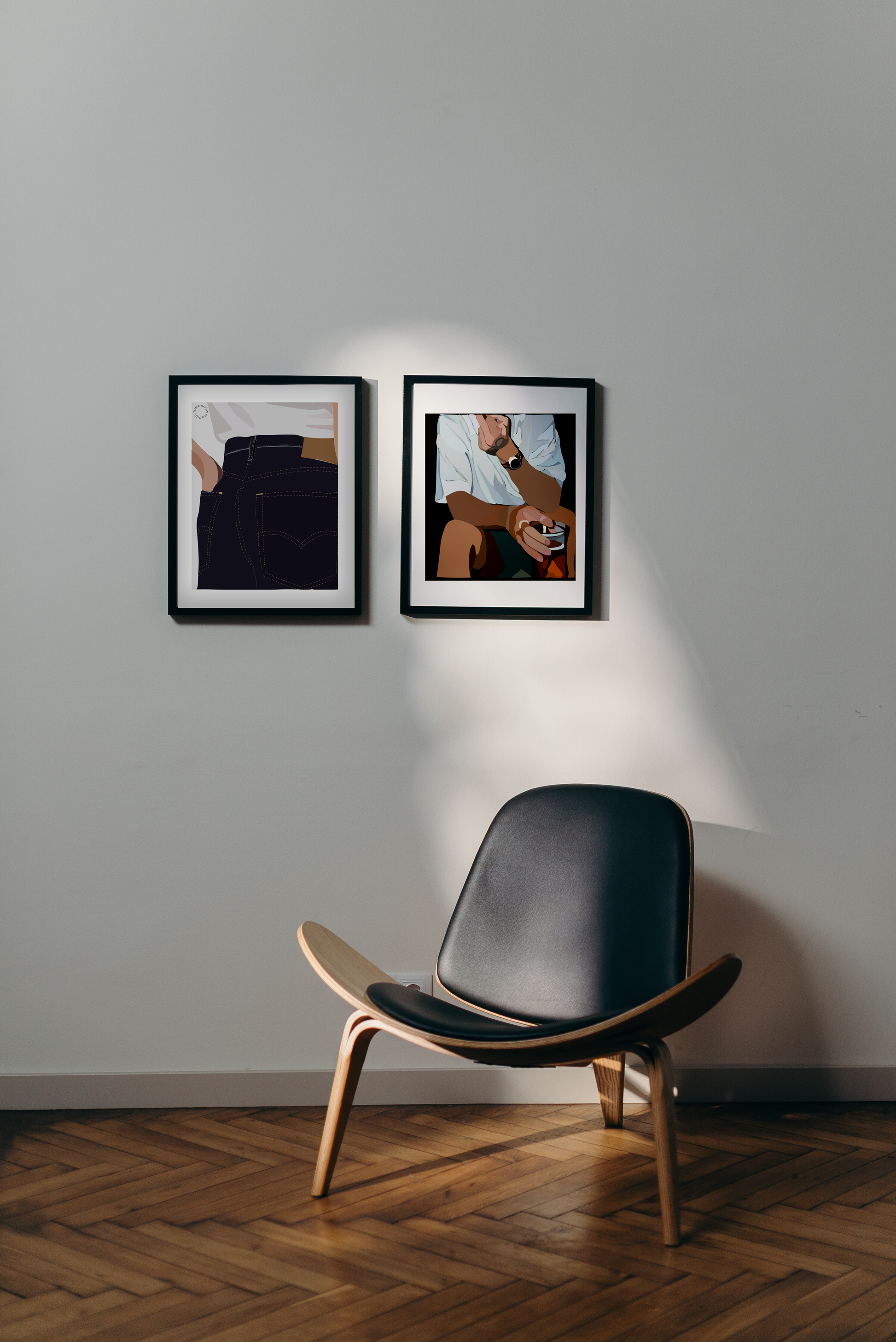 Varmt trægulv og hvid væg, med moderne stol i træ og læder og to Kreative Kunstplakater i grafisk design hængende på væggen i neutrale farver